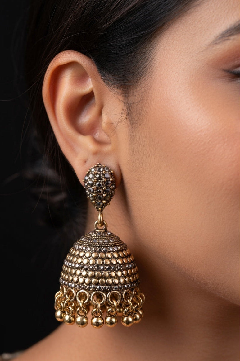 Close-up of a person wearing a gold and silver earring with a dark background